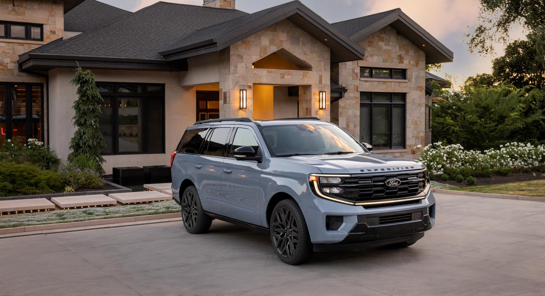 A light blue Ford Expedition parked in front of a nice house.