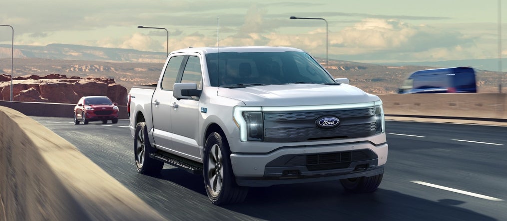 A silver Ford F-150 driving over a highway bridge in a desert.
