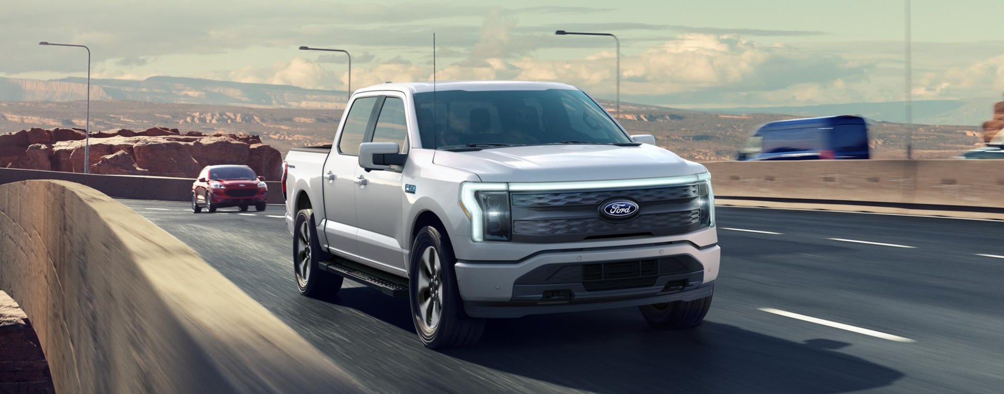 A silver Ford F-150 driving over a bridge on a desert highway.