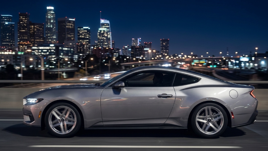 Driver-side profile of a silver Ford Mustang driving at night