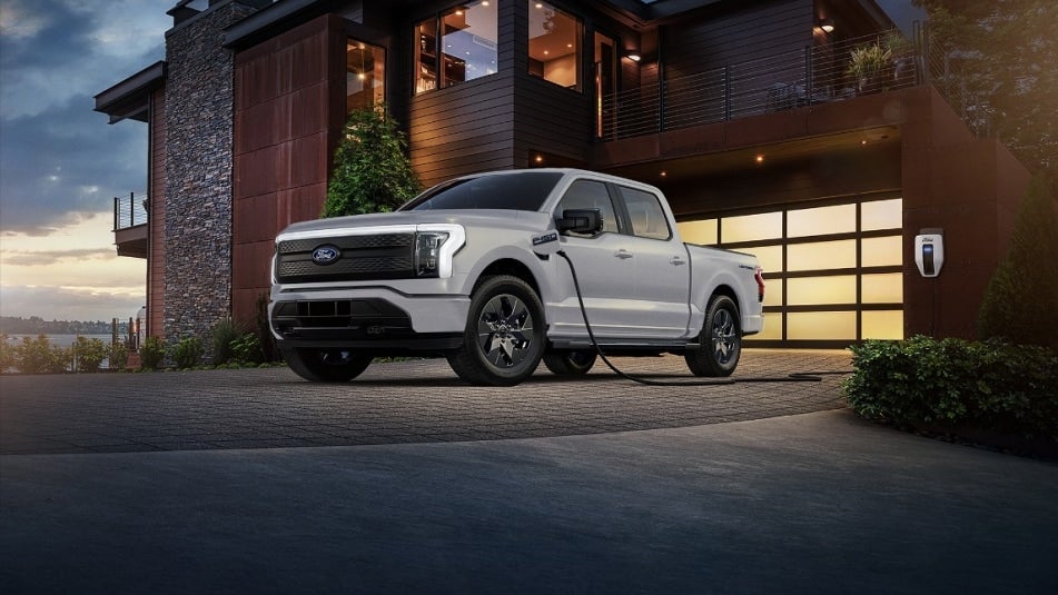 White electric Ford F-150 charging in a driveway.