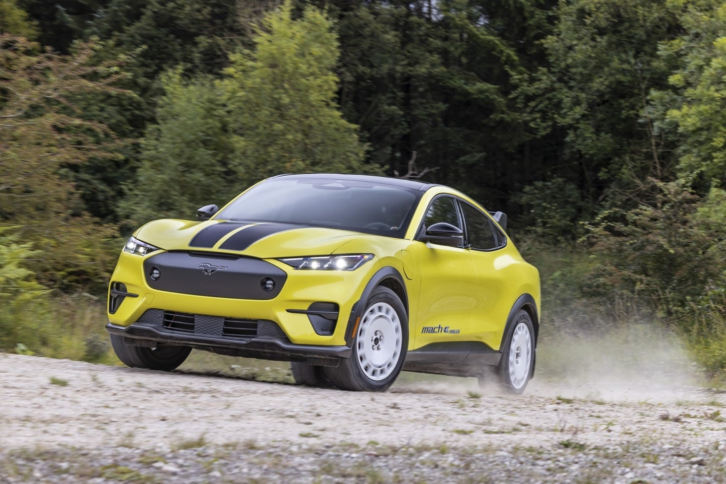 A yellow 2024 Ford Mustang Mach-E, driving on a dirt road.