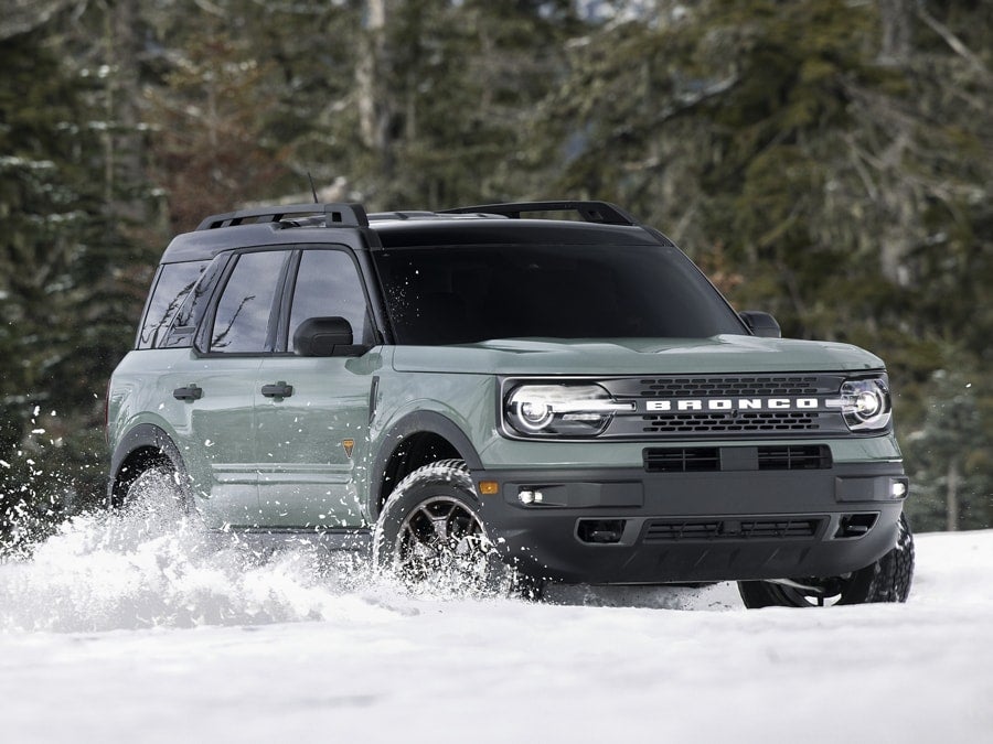 A green 2025 Ford Bronco Sport driving through snow.